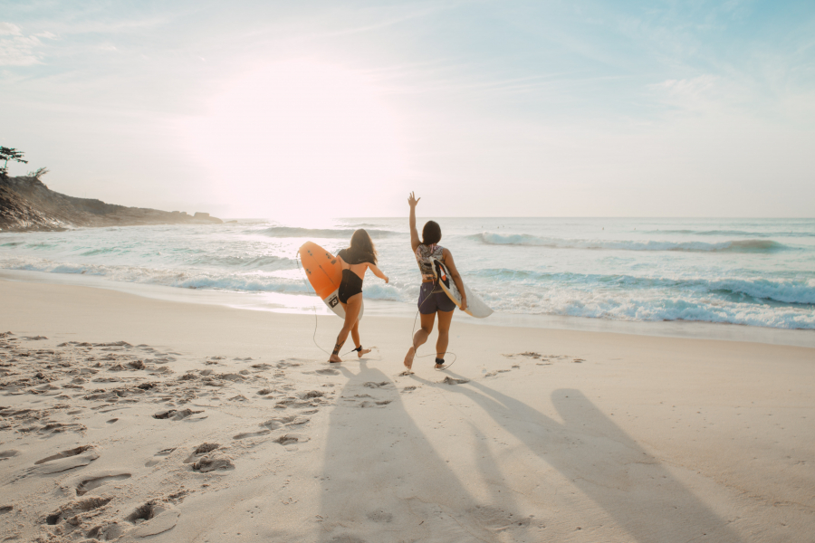 sunrise and two women at a sandy beach going surfing